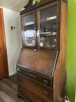 an antique/vintage slant-front secretary desk with a glass-door bookcase top, likely late 19th/early 20th century