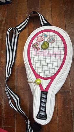 Betsey Johnson XO Volley tennis racquet crossbody bag featuring pink trim, embroidered tennis-themed patches, and a unique tennis ball zipper pull