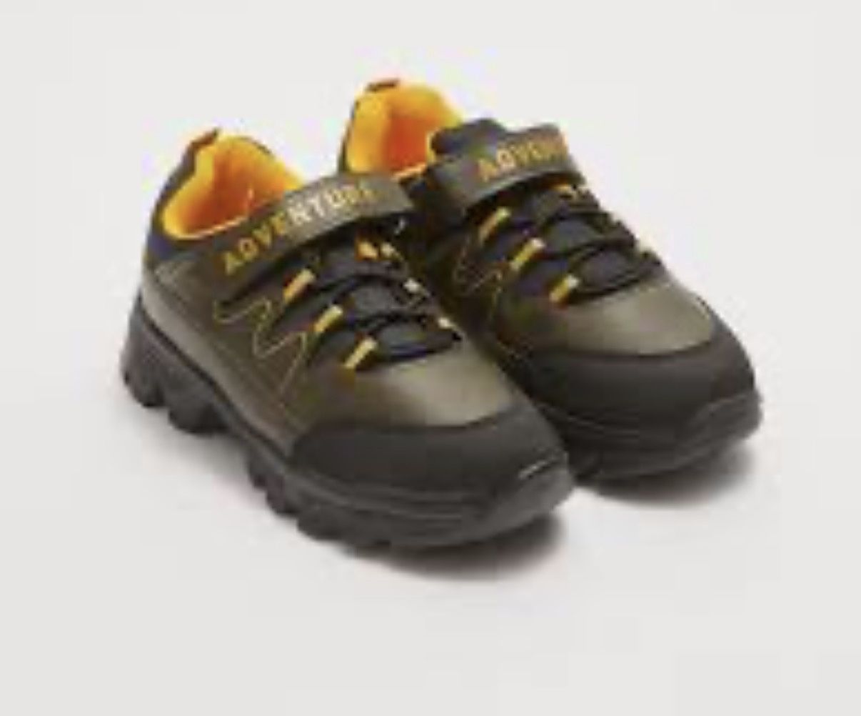 This is a pair of kids' black and yellow trekking shoes with a hook-and-loop strap labeled "ADVENTURE".