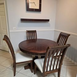 Round wooden dining table with a pedestal base. 