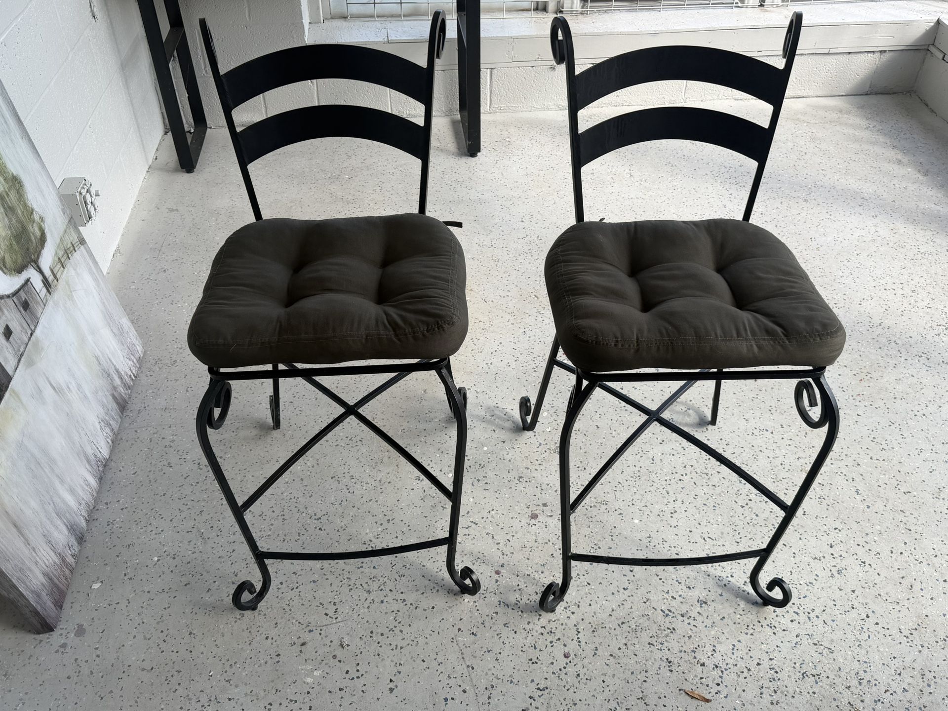 2 Beautiful wrought iron chairs featuring scrollwork legs and plush tufted cushions.