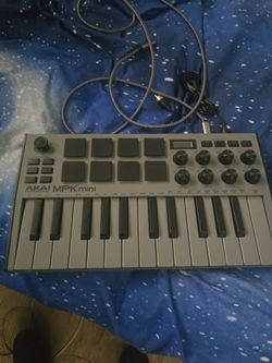 Akai Professional and the model is the MPK mini (specifically the MPK mini MK3 in the grey colorway).