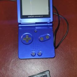Nintendo Game Boy Advance SP in a cobalt blue color, along with its charger and a game cartridge. It features a clamshell design to protect the screen