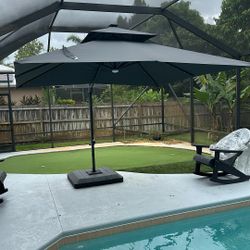 Dark gray patio umbrella with weighted base 10’ x 10’