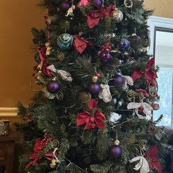 Tall artificial Christmas tree with ornaments and star topper. 7 ft