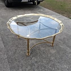 Hollywood Regency style coffee table features a scalloped-edge glass top with a brass base, likely manufactured in Italy 