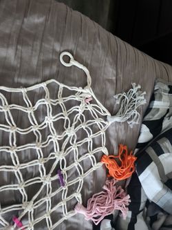 This is a white woven cotton rope stuffed animal hammock.