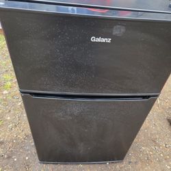 Black Galanz 3.1 Cu ft Two Door Mini Fridge with a top freezer compartment.