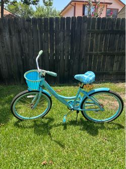 24-inch Kent La Jolla Girls Cruiser Bike in light blue with a plaid seat and front basket.
