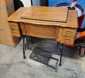 vintage White rotary treadle sewing machine in an oak cabinet.