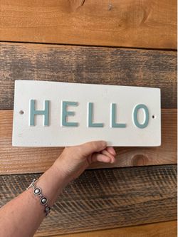 Hearth & Hand with Magnolia 'Hello' Wall Sign Cast iron wall sign is from the Hearth & Hand with Magnolia collection. It has a white textured backgr