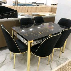 Dining set with a rectangular black marble table with gold veining and six black upholstered chairs with gold legs