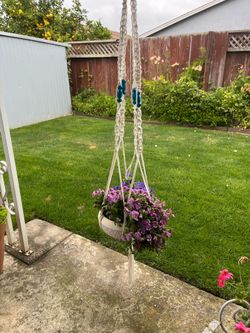 Colorful macrame hanging planter has white braided cord and blue beads. Pot of Flowers Are not included.