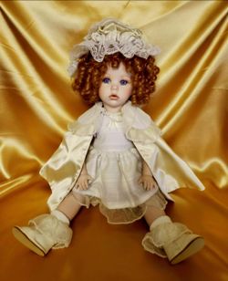 " porcelain doll modeled after Shirley Temple, featuring auburn curly hair and purple eyes. It includes an outfit and is made by the brand Dianna Effn