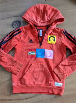 Adidas x LEGO kids hoodie in bright orange with LEGO graphic design on the front and Adidas three-stripe sleeves. Size 7
