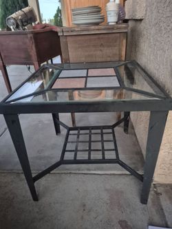 metal and glass end table with inlaid tile or slate accents.