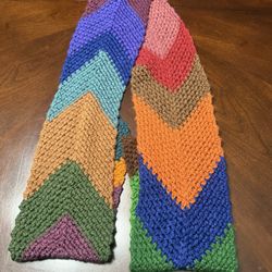 Beautiful handmade crochet scarf featuring a bold multicolor chevron/patchwork design. This scarf showcases rich earth tones and vibrant shades includ