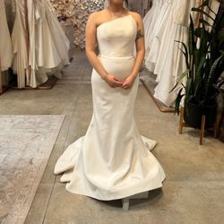 Romona Keveza Strapless gown made of silk crepe, features an asymmetrical neckline and a fluted skirt. 