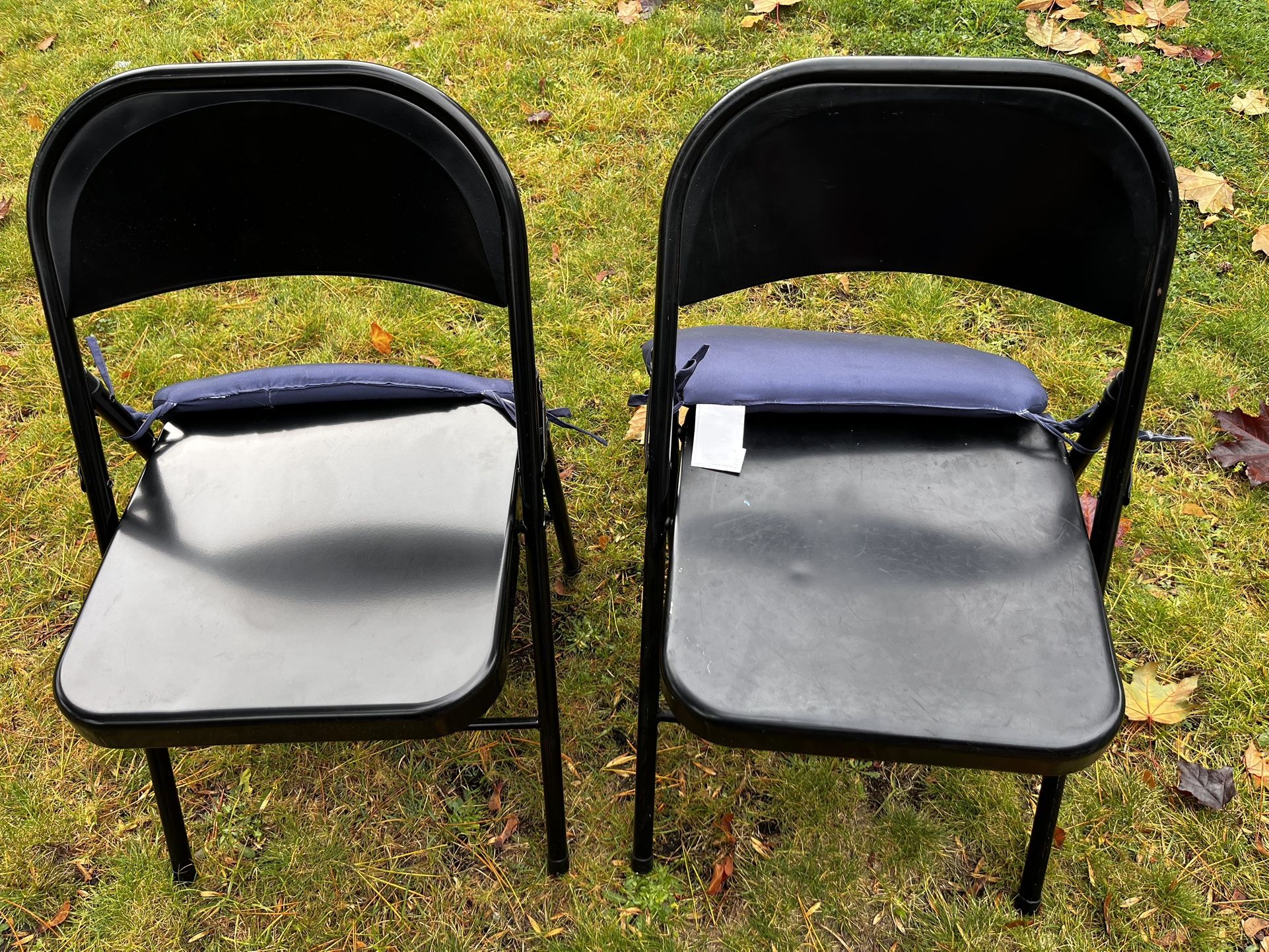 Two Black Metal Folding Chairs With Blue Coushions. Can keep or toss cushions.
