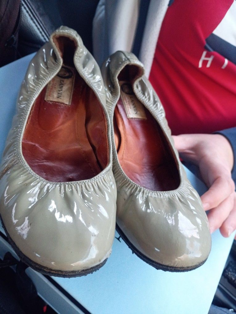 These are likely Prada women's metallic leather driving loafers. This style of flat, slip-on shoe is characteristic of the Prada brand, featuring a me