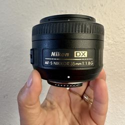 Nikon AF-S DX NIKKOR 35mm f/1.8G Lens with caps for front and rear, hood, and bag. 