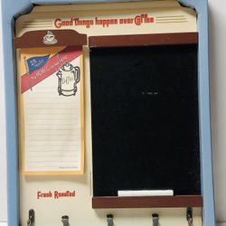 Message board, 13 1/2 inches high, 11 inches wide. Has note pad, chalkboard, 2 pegs or hooks to hold keys, 3 decorative clips to hold coupons or notes