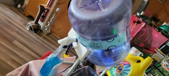 Water gallon container w locking lid and a stand tilting it for easy pour