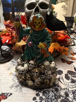 La Muerte with green hood. With skulls at his feet in chains Halloween decoration
