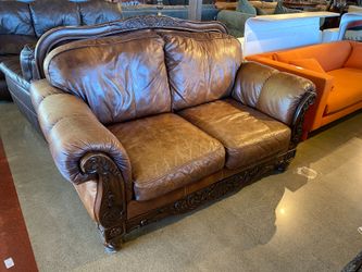Ornate Brown Leather Loveseat with Rolled Arms and Carved Details