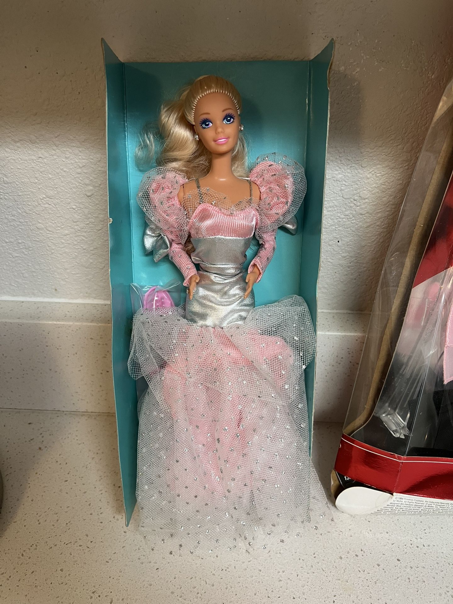 1990 Evening Elegance Barbie doll. This doll was a J.C. Penney catalog exclusive. It has blonde, wavy hair and blue eyes. The doll wears a pink and