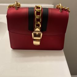 This is a brand new red and black purse with a gold chain.