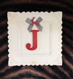 Monogram plaque with red capital letter "J” accented with a gingham fabric  black-and-white checkered bow