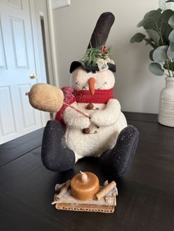 Primitive snowman roasting marshmallow over campfire