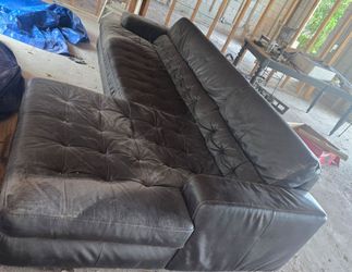 A large, dark brown leather tufted sectional sofa