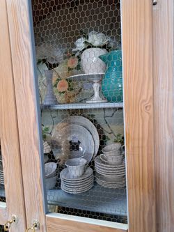 Armoire with chicken wire inset in the doors and handpainted floral motif inside