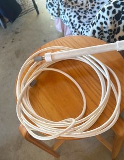 White coaxial cable has F-type connectors on both ends. This cable is made of a flexible plastic outer jacket and is coiled for storage.