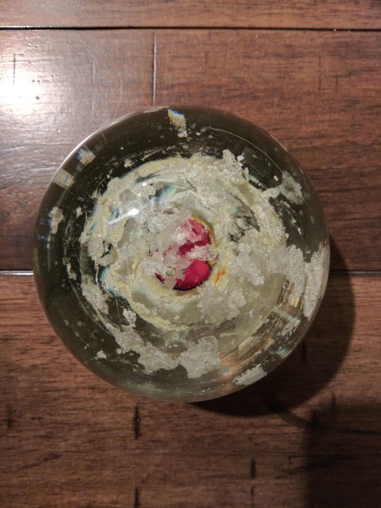 Glass Paperweight with red berry In cased In a white base with white flakes.