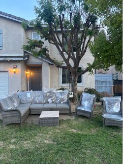 L shaped outdoor patio couch with 2 club chairs and a glass coffee table