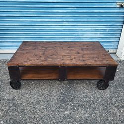 Mountainier coffee table. Industrial style with iron wheels. Measures approx: 52" wide x 32" deep x 17" tall 