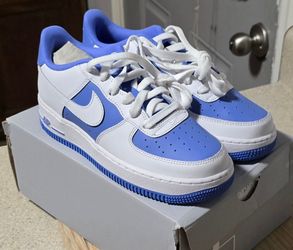 These are Nike Air Force 1 Low GS sneakers, identifiable by their iconic silhouette and vibrant blue overlays.
