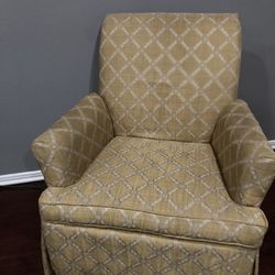 upholstered armchair with a rolled arm, low back, and a skirted base, featuring a gold and white geometric lattice pattern.