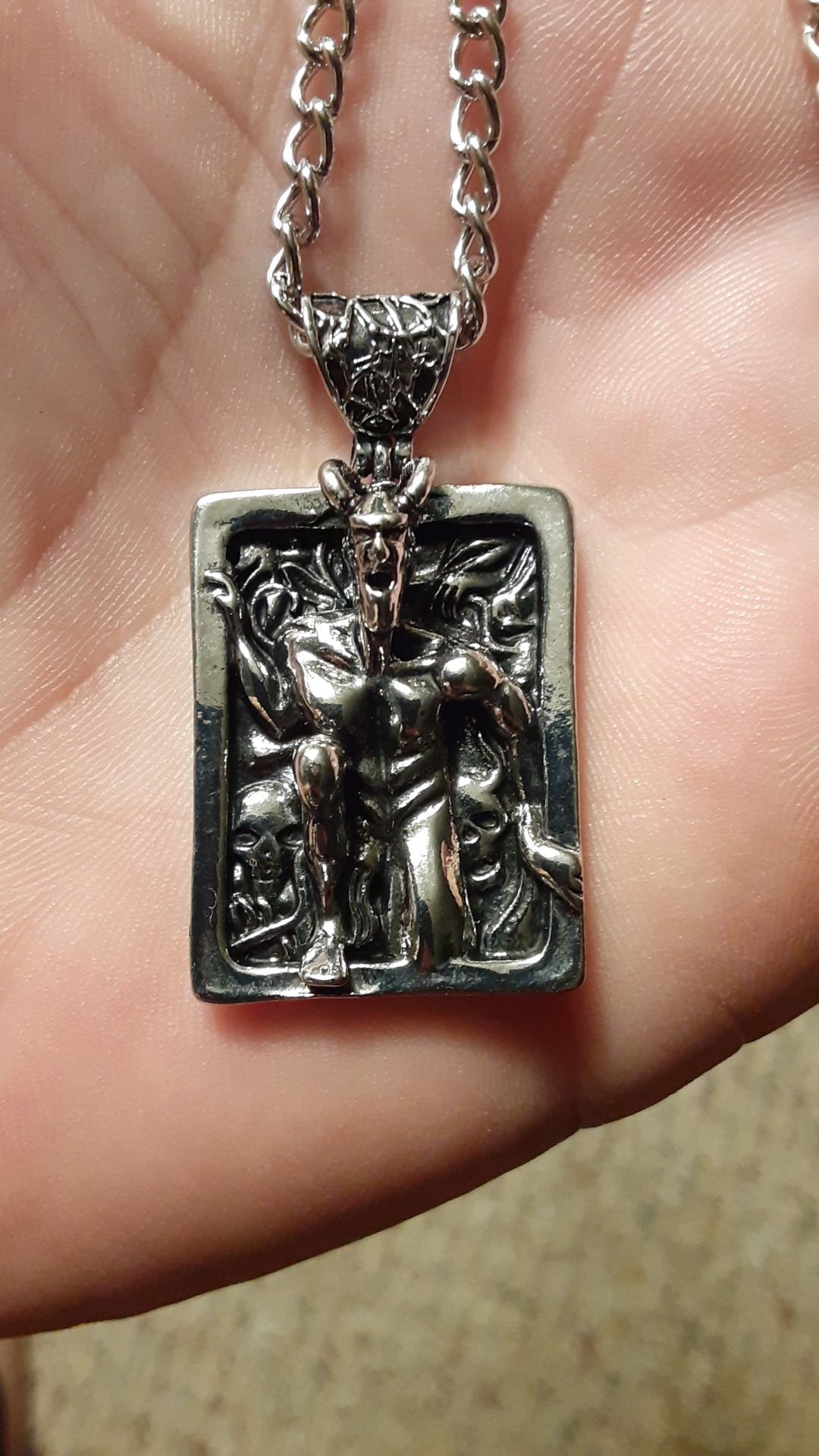 silver necklace and pendant of devil coming out of he..