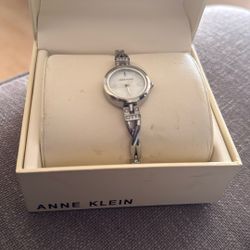 Anne Klein silver-tone women's watch with a mother-of-pearl dial and a twisted bangle bracelet accented with premium crystals.  