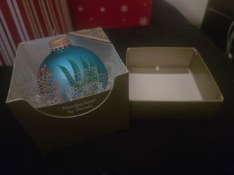 hand-painted blue glass coastal Christmas ornament featuring a sandy beach design with starfish and coral, accompanied by a business card for Southwes
