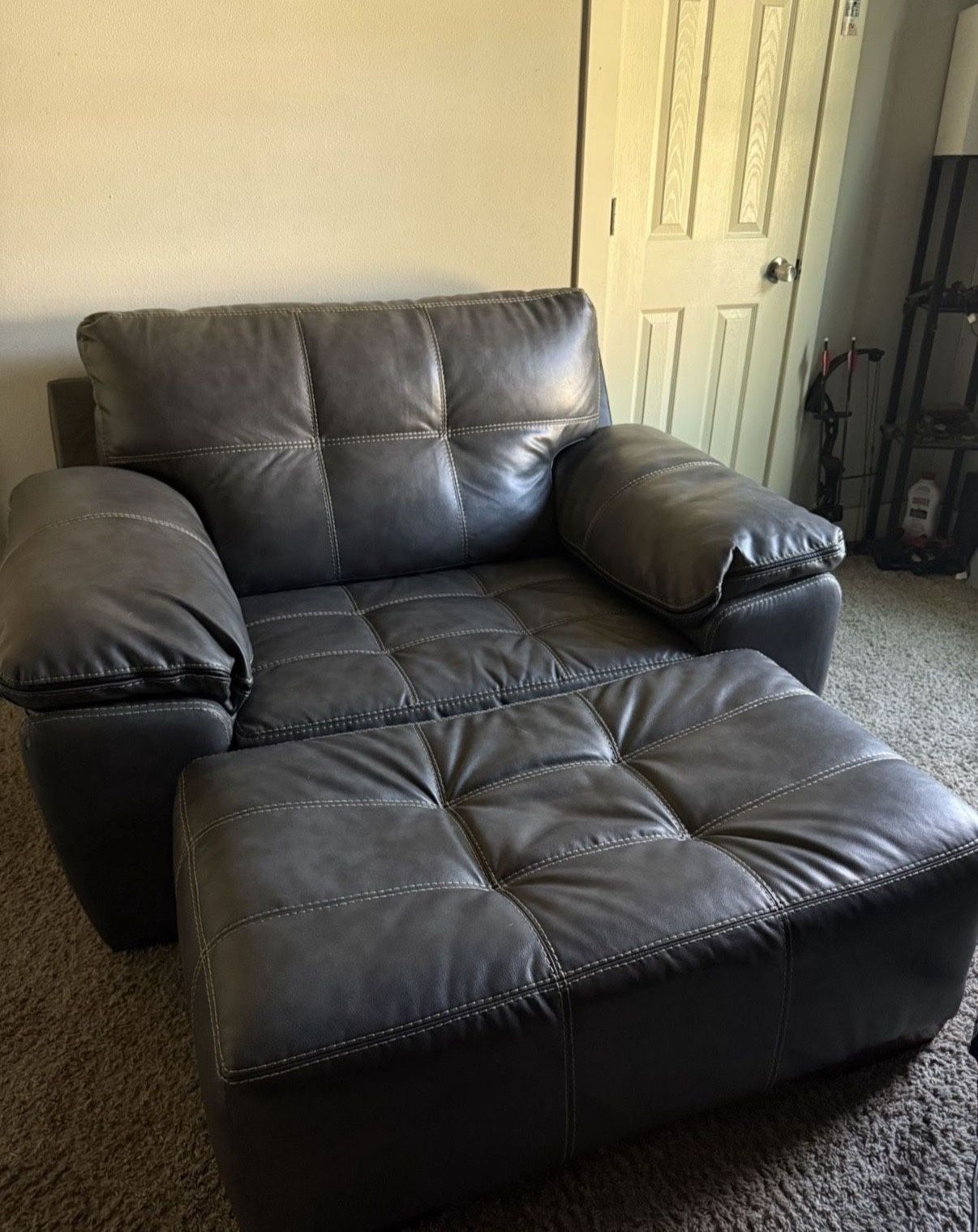 Grey tufted leather armchair with an accompanying ottoman