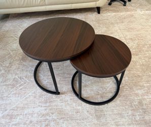 set of modern round nesting coffee tables with dark brown wood-grain tops and black metal semi-circular or crescent bases