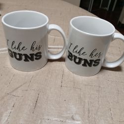 Two Coffee Mugs One Says I Like his Guns And The Other One Says I Like Her Buns