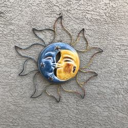 A large terracotta sun face with metal flares 