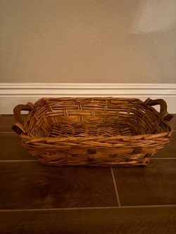 rectangular woven wicker and rattan basket tray with dark carved wooden side handles.