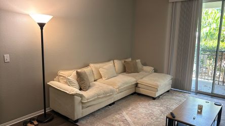 White sectional couch with ottoman and pillows